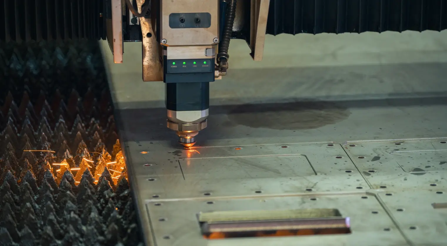 Close-up of a CNC plasma cutting machine cutting an intricate decorative eagle design into a flat metal sheet, with bright sparks flying and a CNC control panel visible in the background.